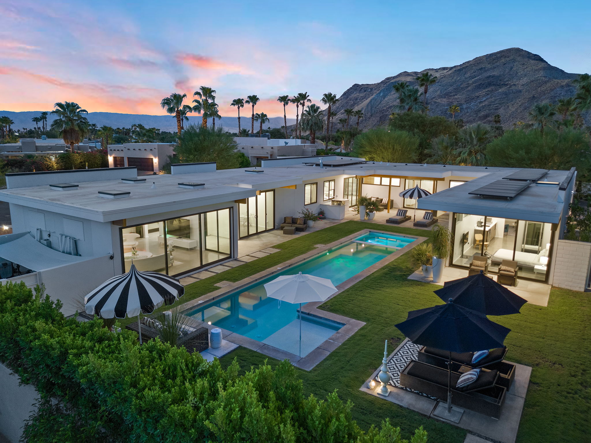 Contemporary desert home and pool at dusk with mountain views